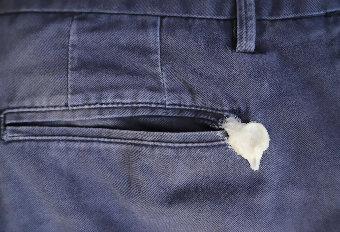 white chewing gum stuck on the back pocket of navy blue denim pants