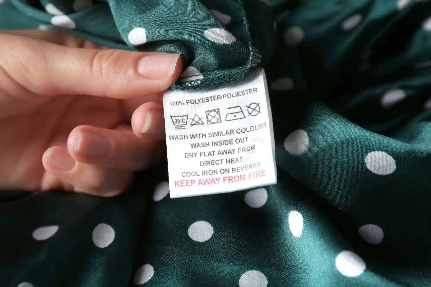 woman reading shirt tag of green shirt that is one hundred percent polyester