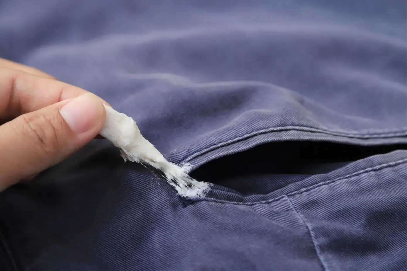 woman removing dried white chewing gum from navy blue pants