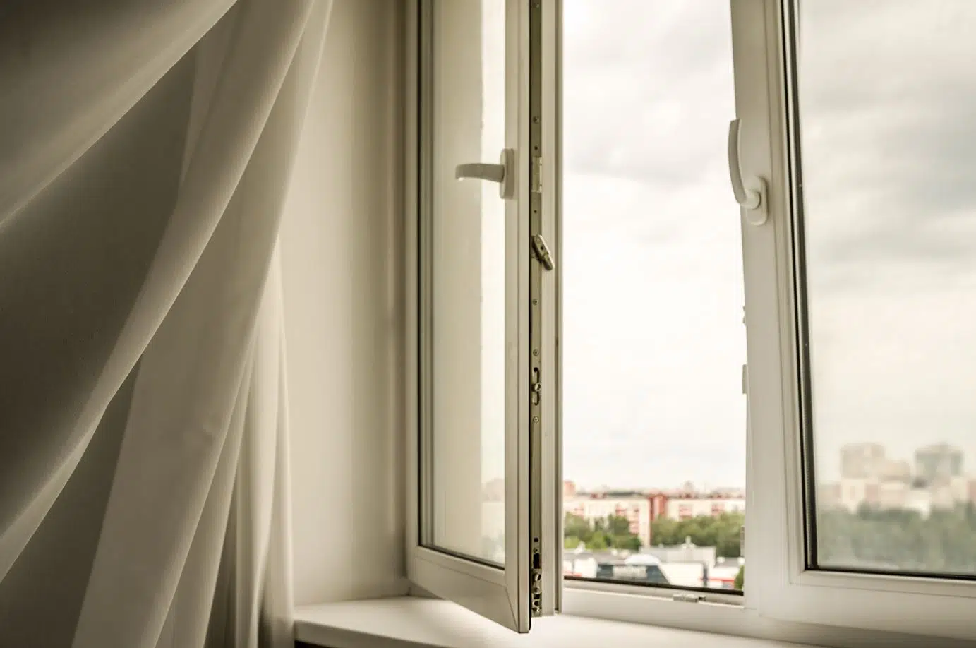 white swaying curtain due to wind next to a large open window