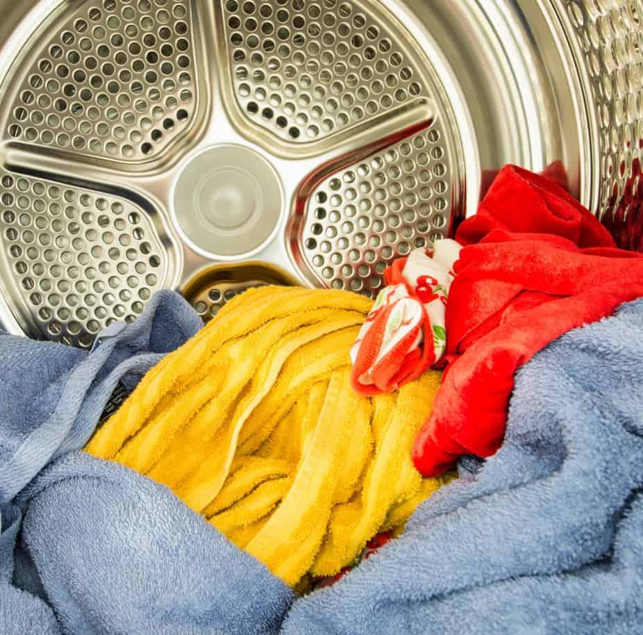 assorted coloured clothes in the drum of a dryer