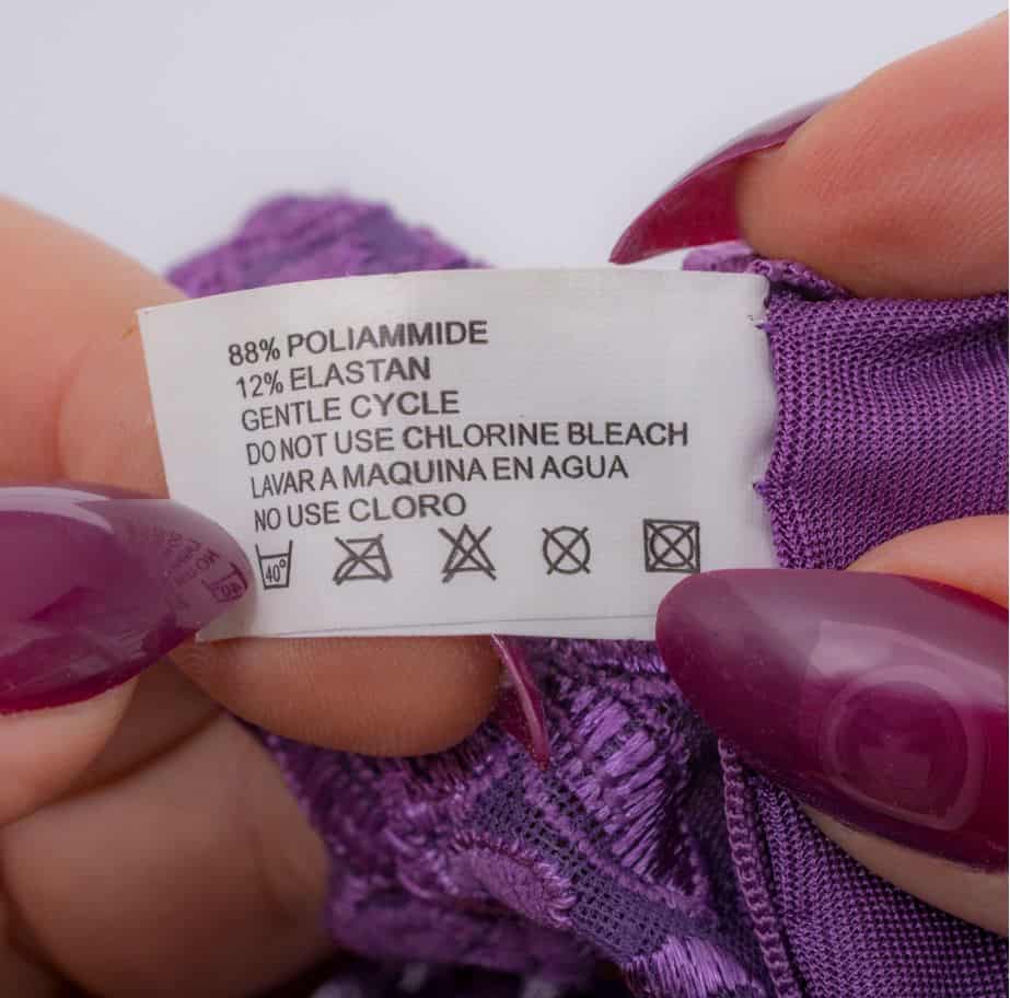 woman with long purple nails checking washing instructions on her bra