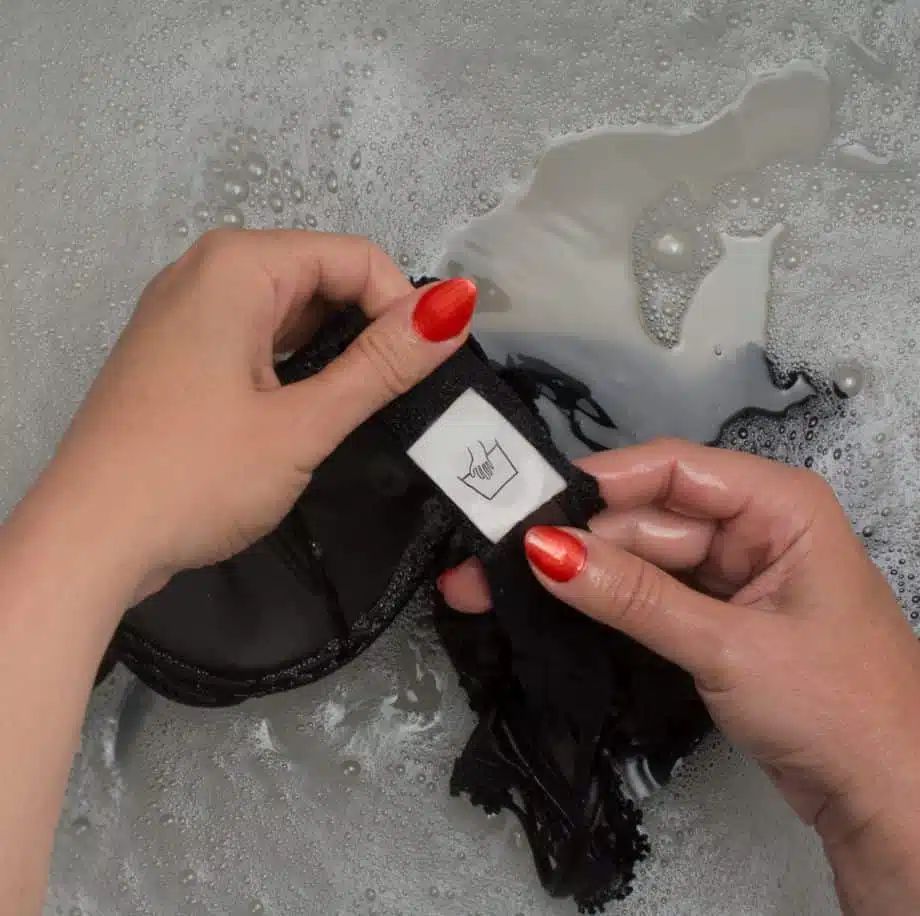 woman with red nail polish handwashing a black bra