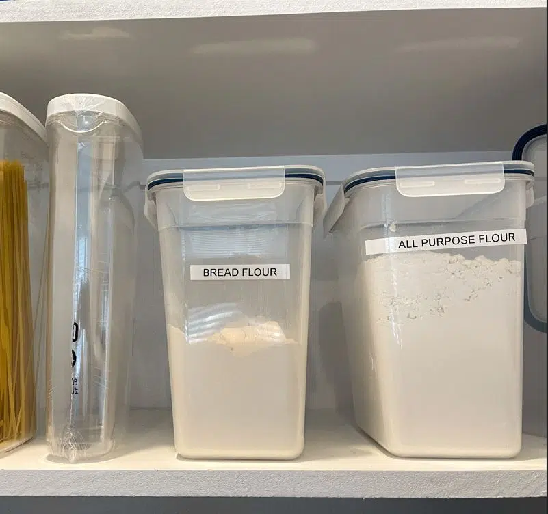 bread flour and all purpose flour in a plastic container in an all-white pantry