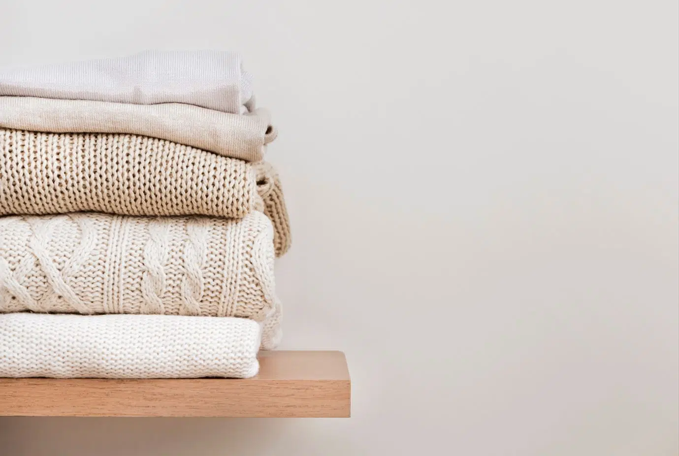 brown and beige clothes neatly folded on a wooden shelf