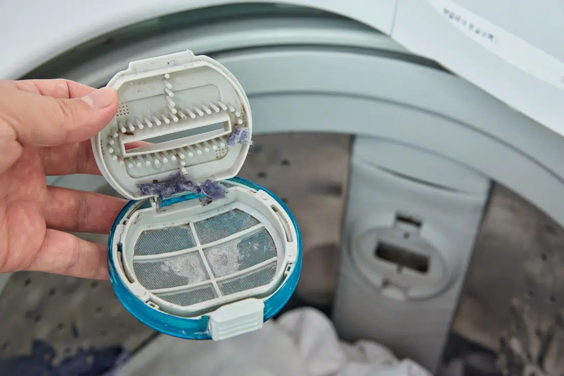 man holding dirty blue washing machine filter