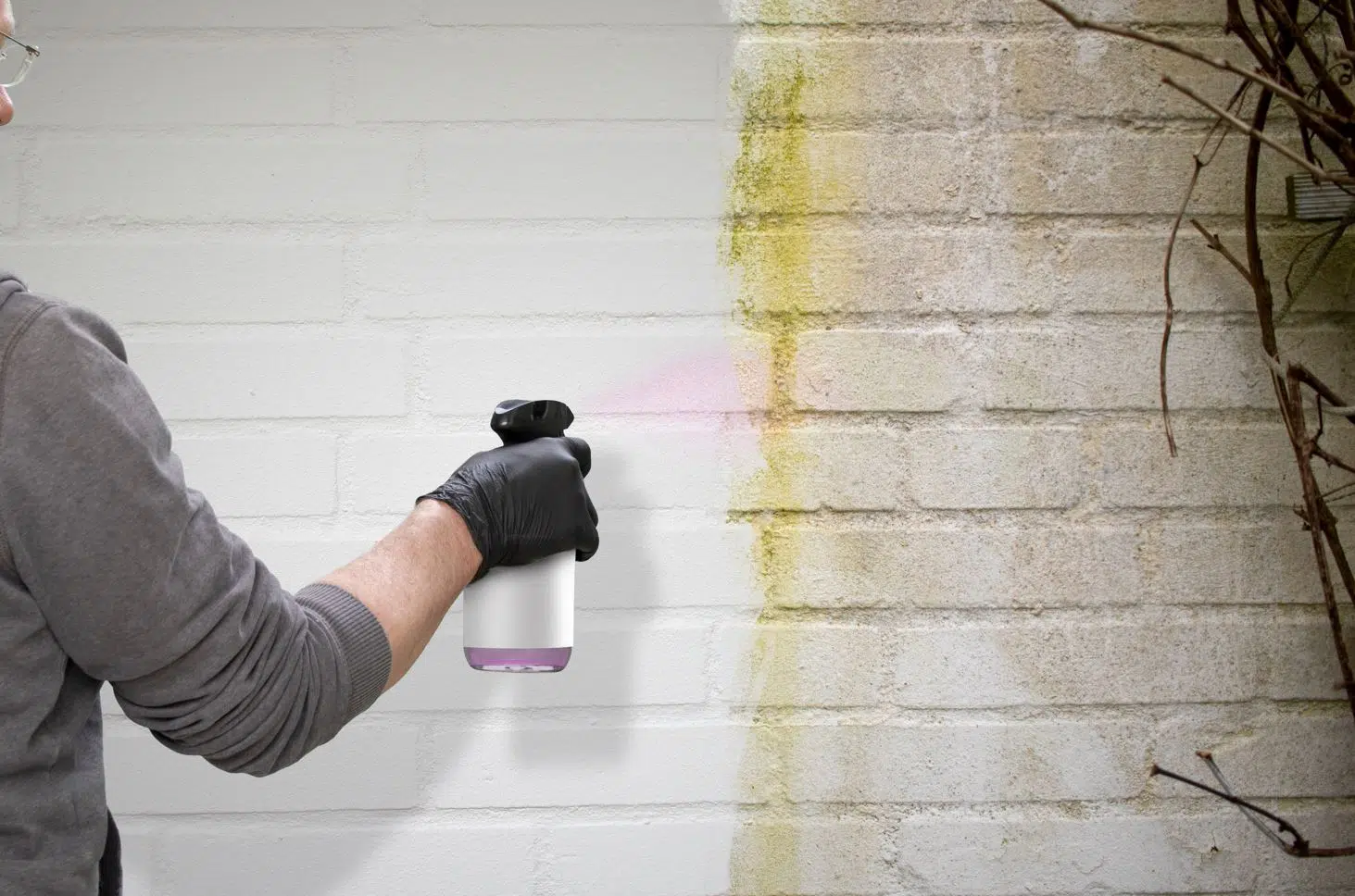 man using a cleaning chemical in a spray bottle to clean a white interior wall