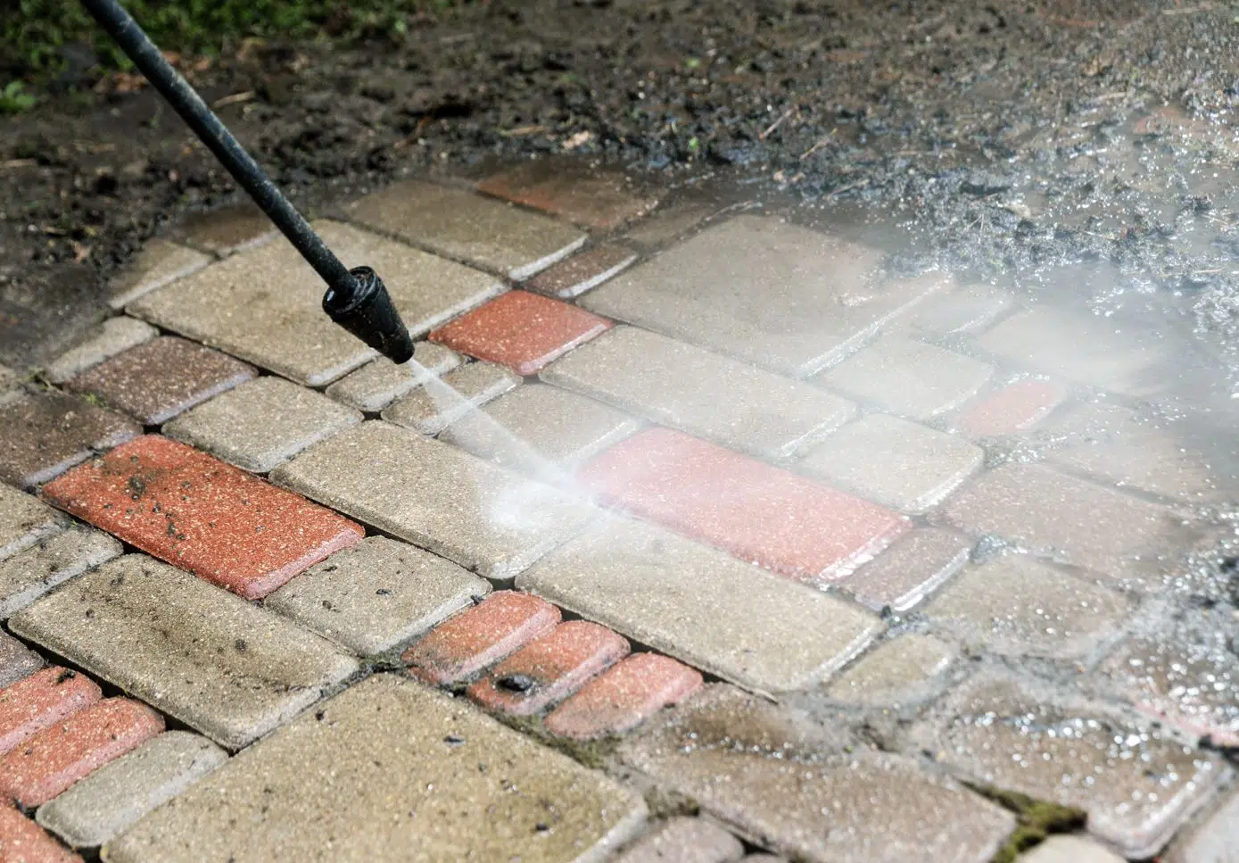 man using pressure washer to pressure washer to clean outside bricks