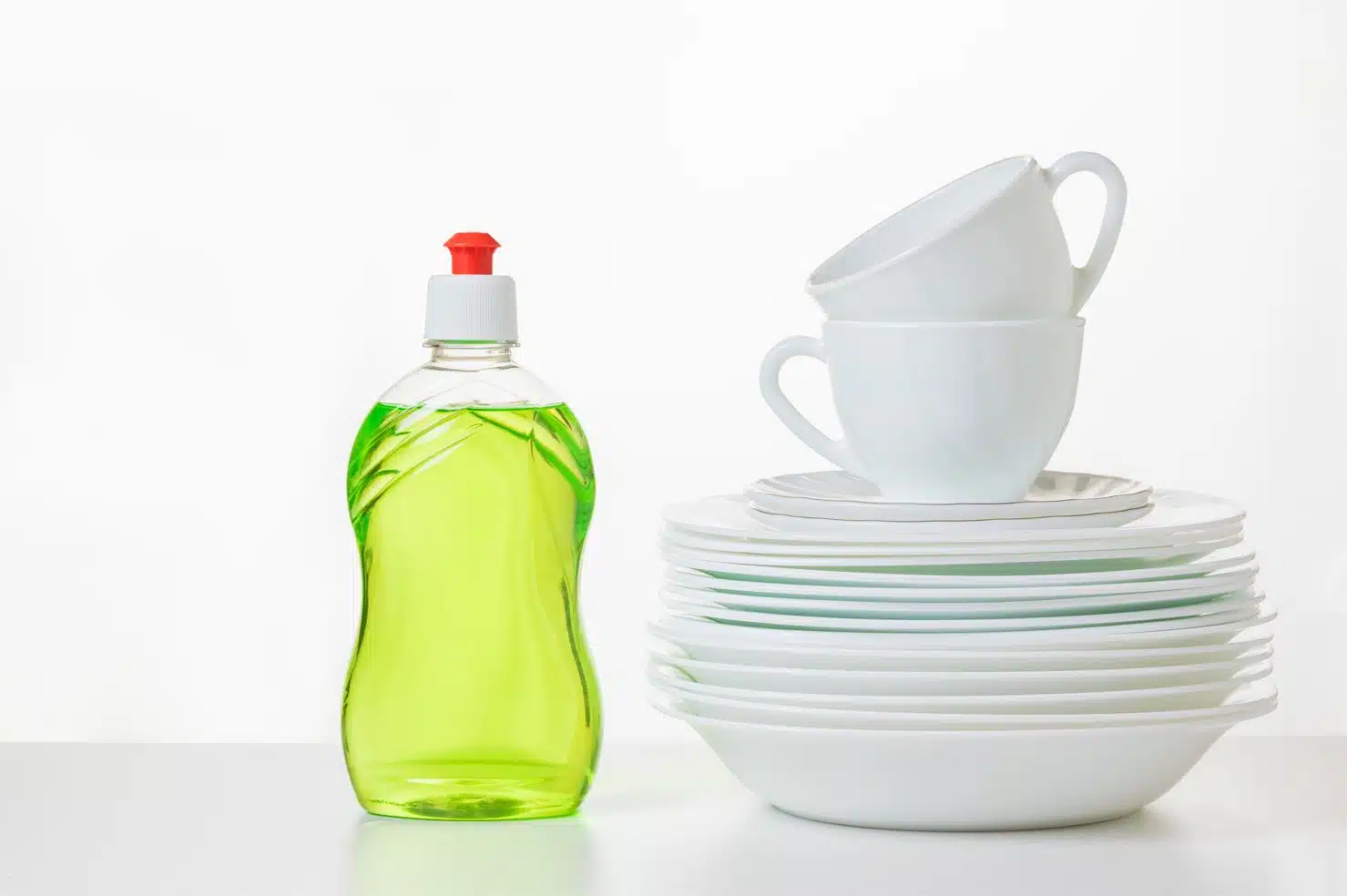dishwashing liquid next to a stack of white plates and bowls