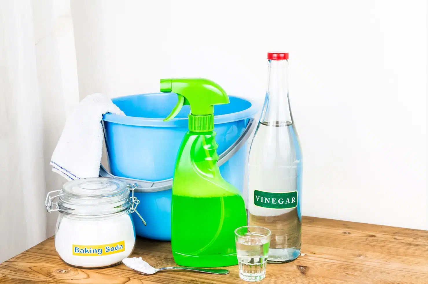 vinegar and assorted cleaning chemicals on a table next to a blue bucket