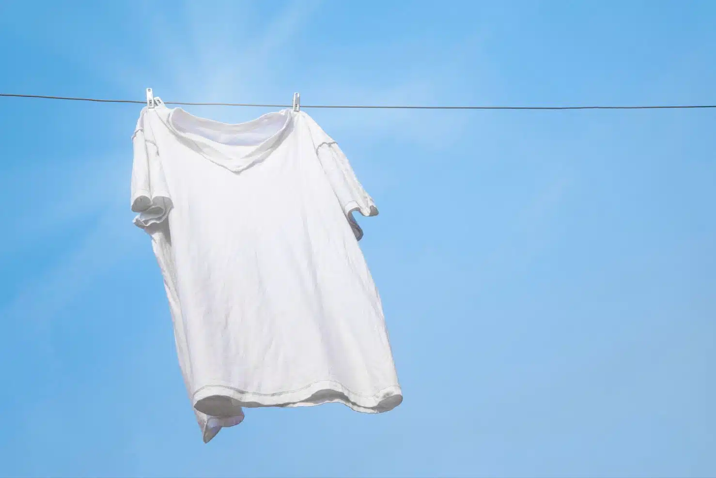 white t-shirt being dried on a clothes line