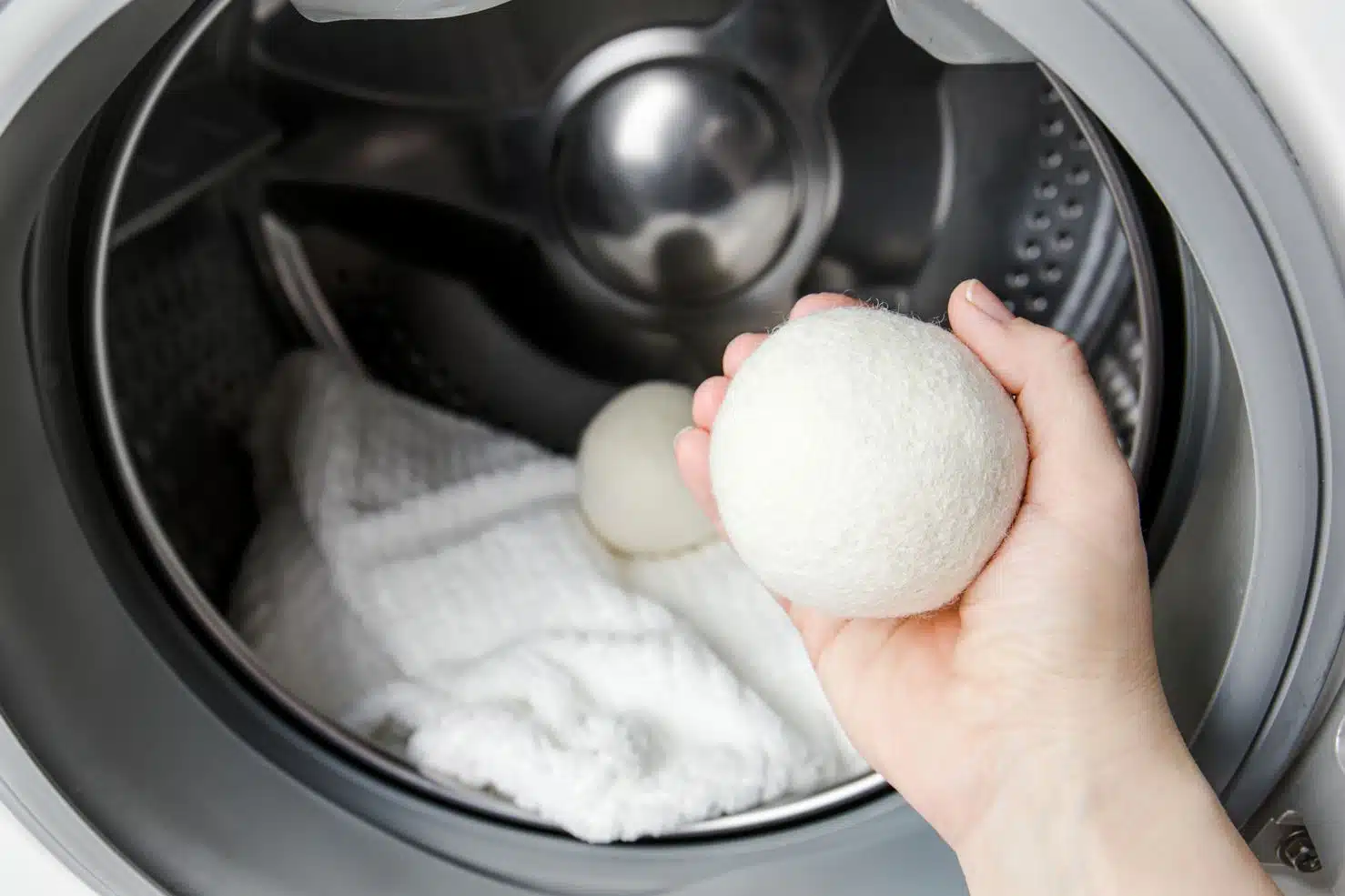woman putting dryer balls into washing machine to prevent static