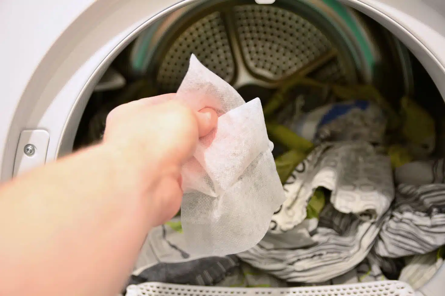 woman putting dryer sheets into full front loaded tumble dryer