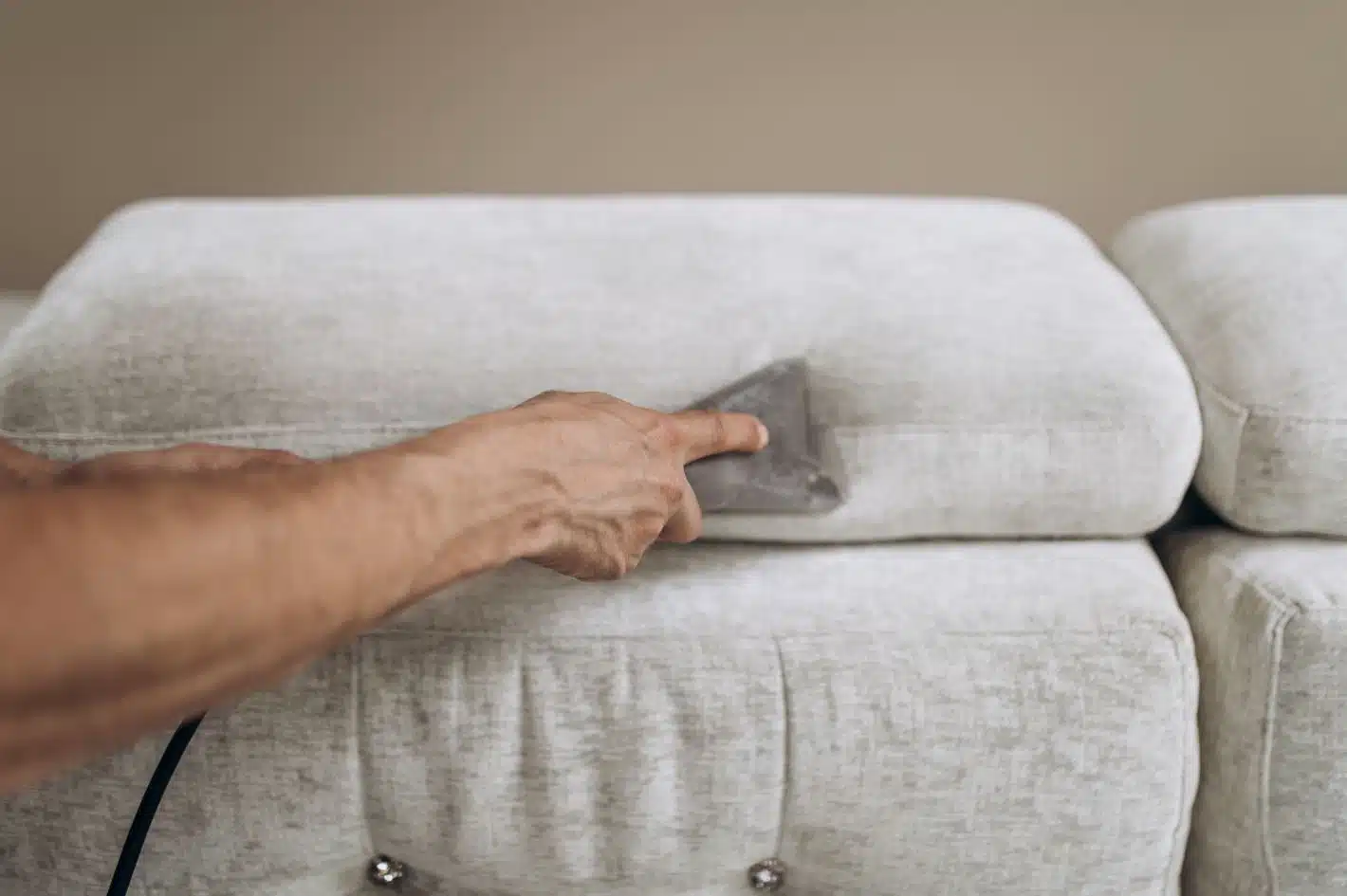 man steam cleaning gray upholstered couch