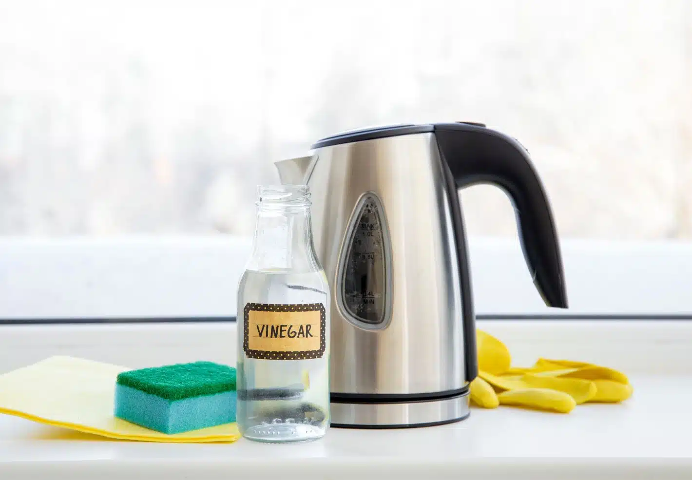 vinegar in a container next to a kettle and cleaning supplies