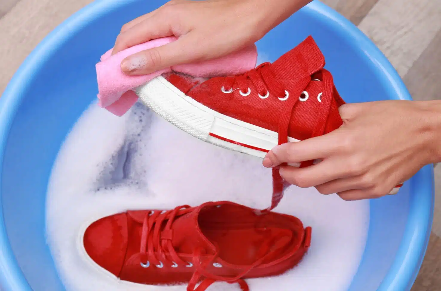 woman hand washing red converse all stars in a blue basin