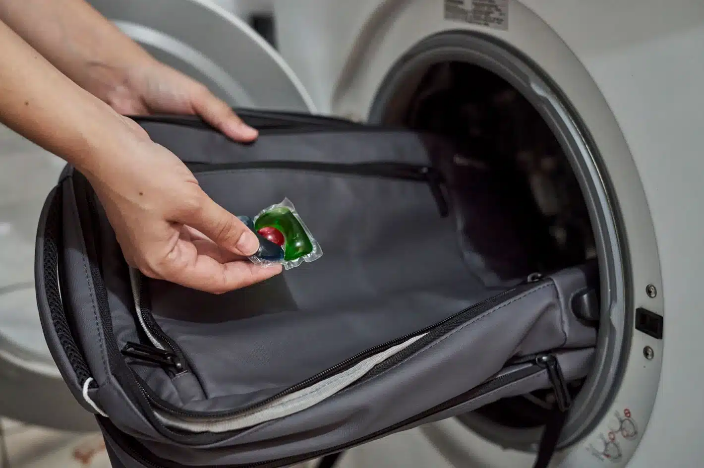 man placing gray bag into washing machine
