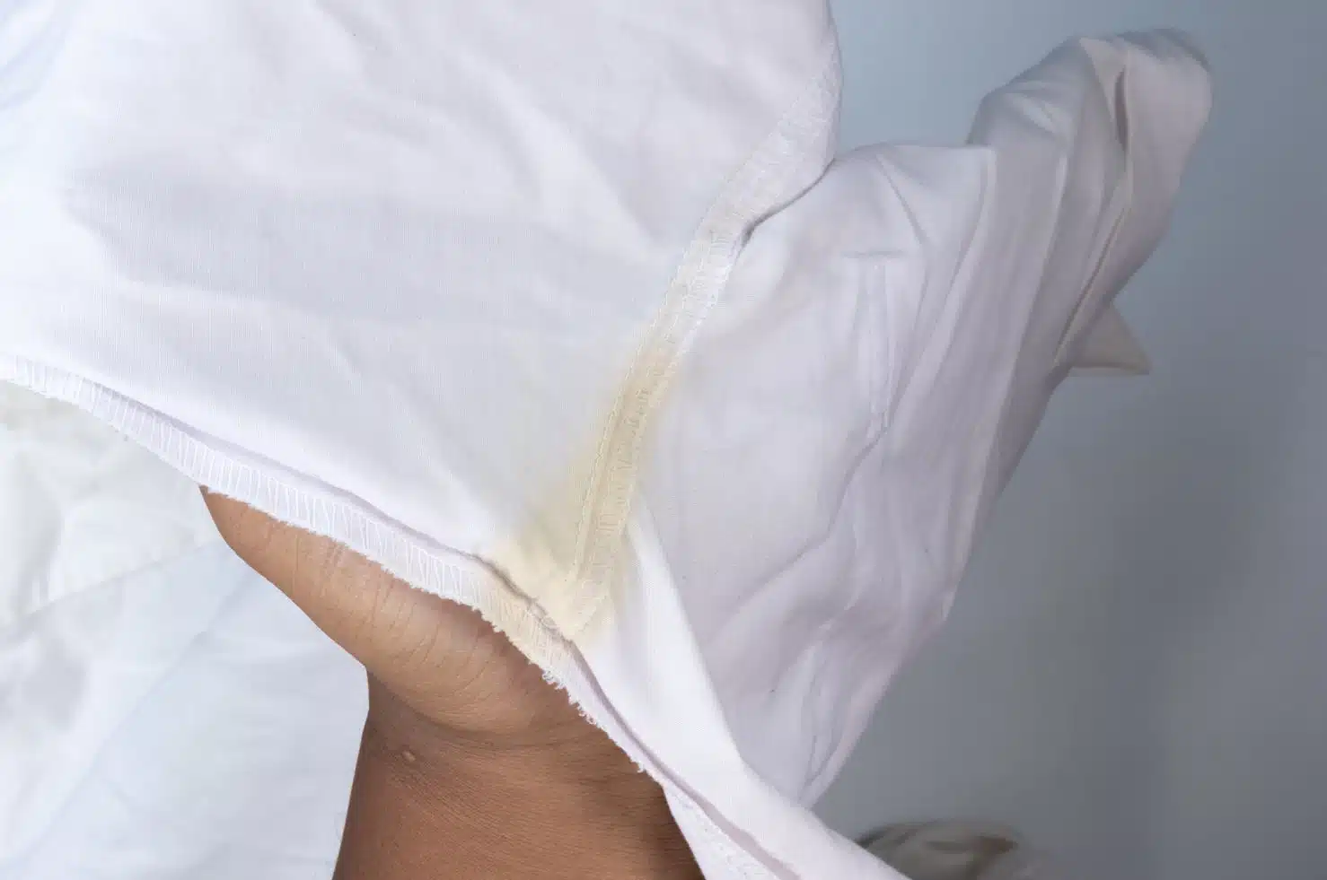 woman holding up white shirt with deoderant stain