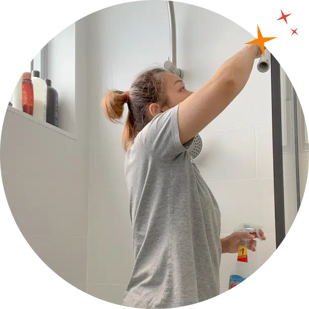 MaidForYou cleaner Mikki using glass cleaner to scrub a glass shower screen