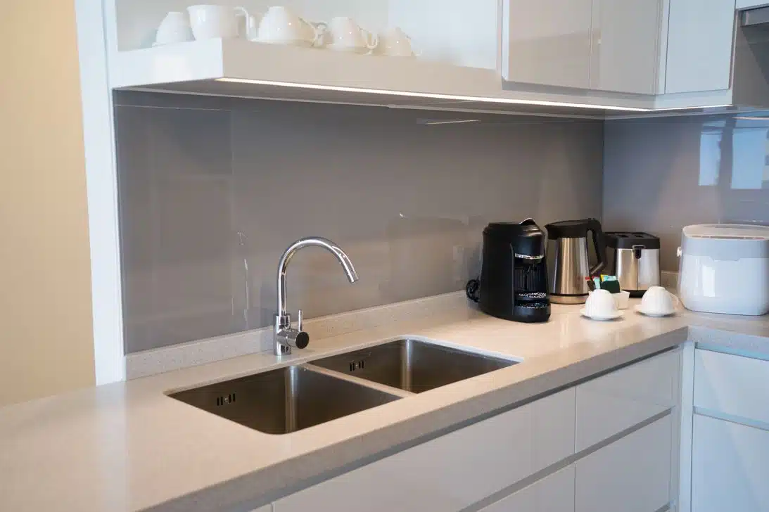 minimalistic clean kitchen with stainless steel sink and stone benchtop