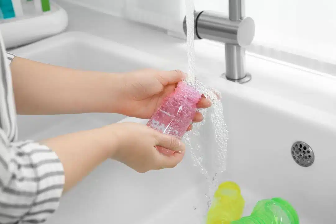 woman running pink baby bottle under bathroom tap