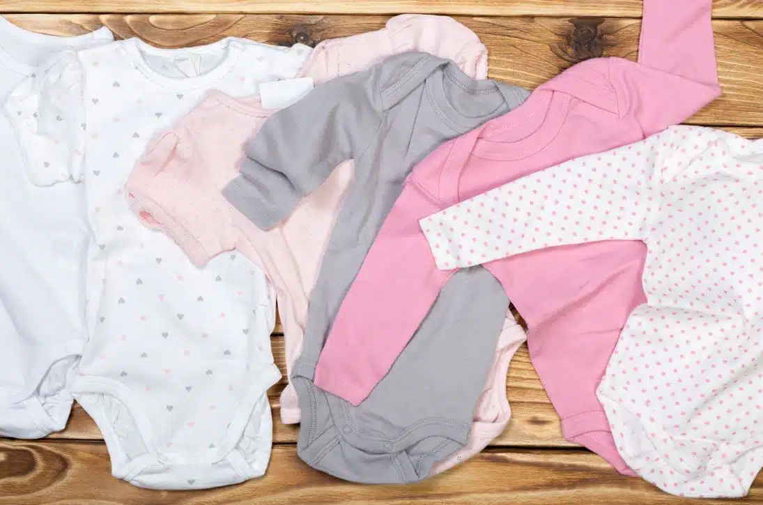 assorted coloured baby onesies and rompers on a wooden countertop
