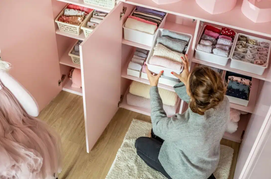 woman organising baby clothes in pink closet