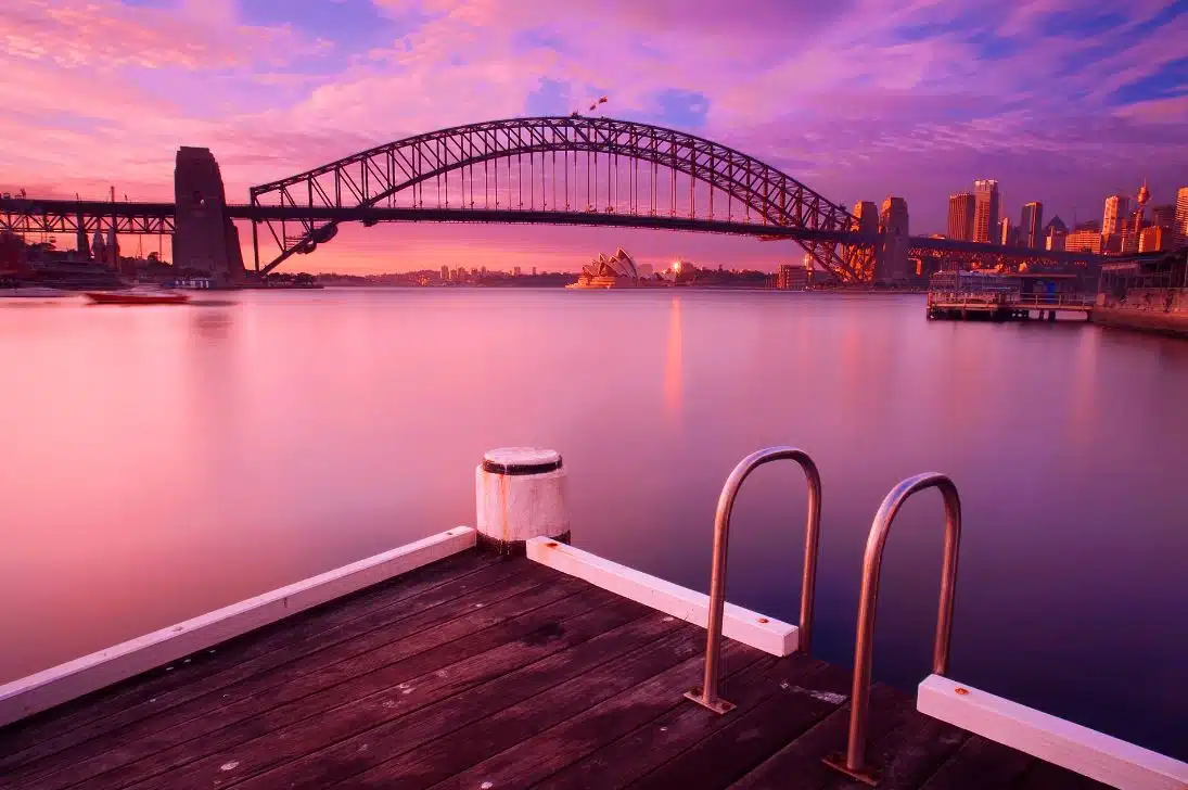 a view of Sydney Harbour at dusk during winter with the Harbour Bridge and Opera House in the background
