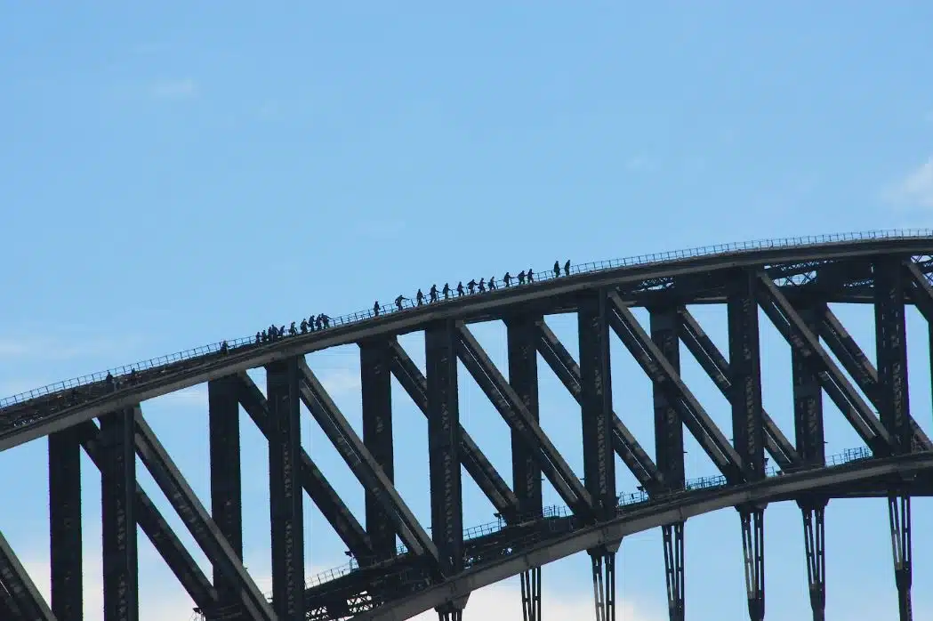top view of Sydney Harbour Bridge with people climbing to the top in the background