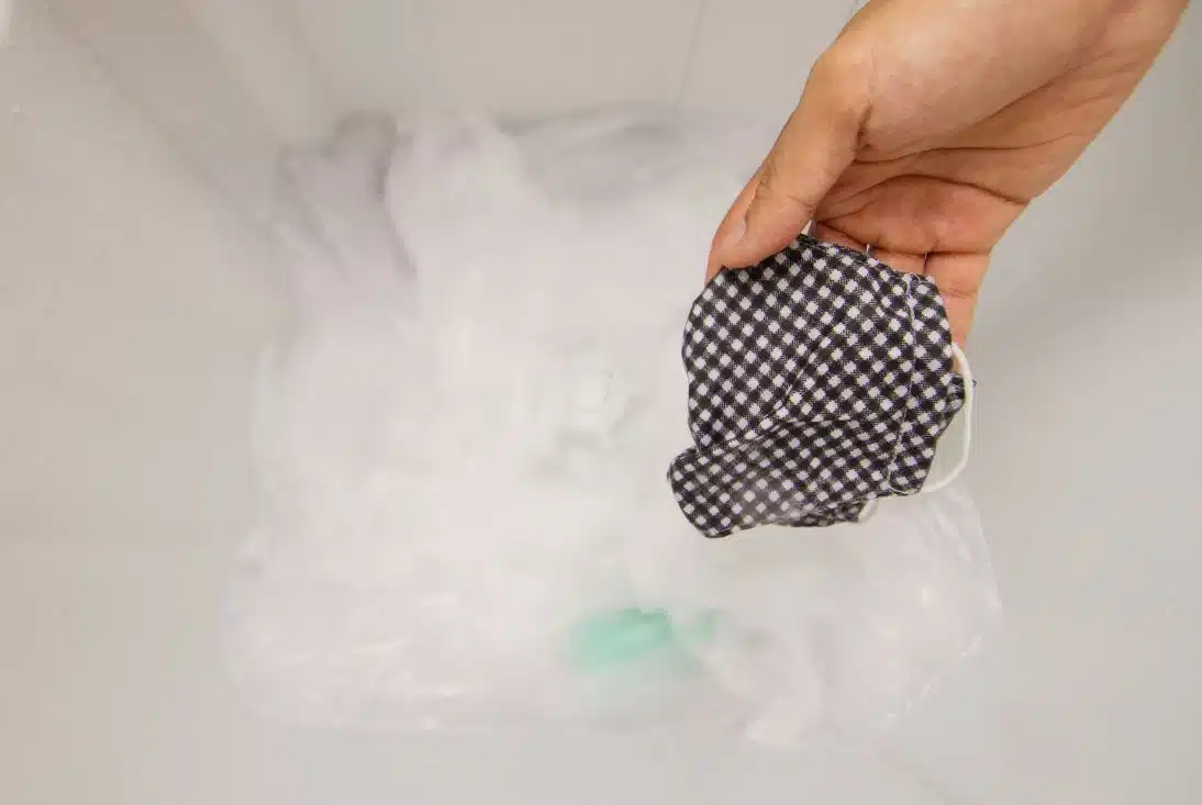 woman washing white fabric in a top loader washing machine