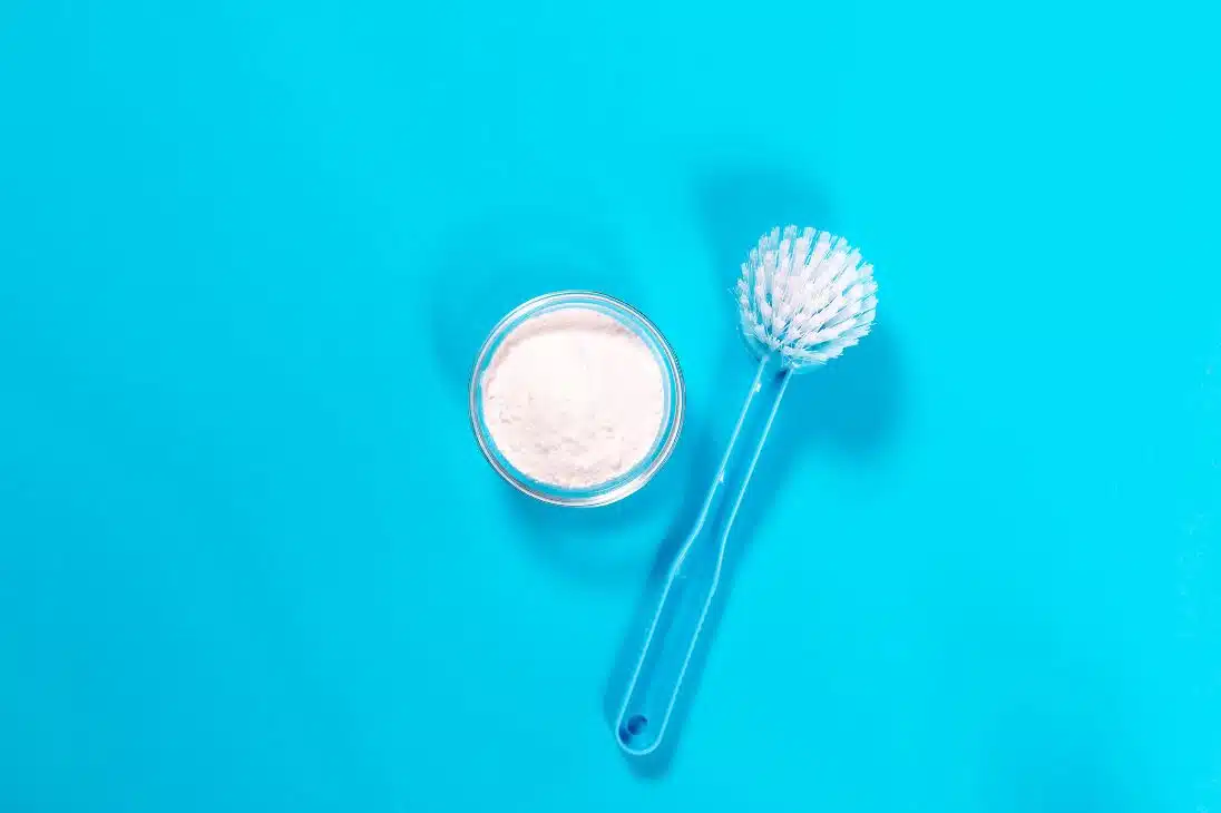 baking powder and scrubbing brush on a blue background