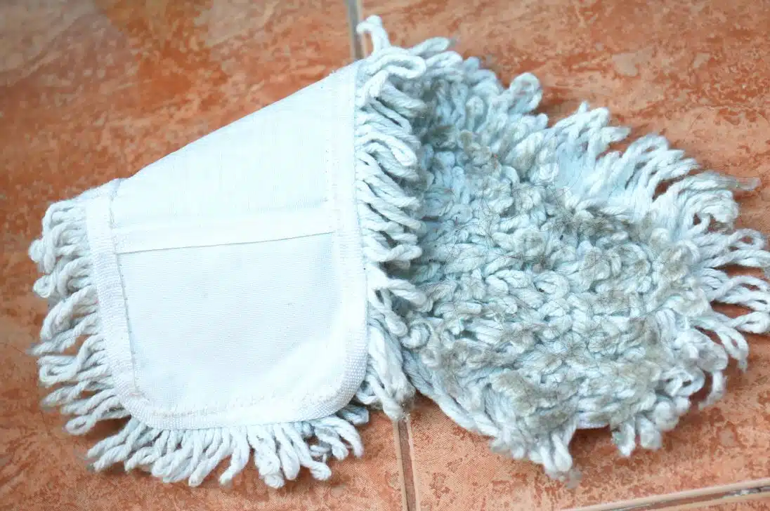 close up of dirty blue steam mop pad folded in half on a red tiled floor