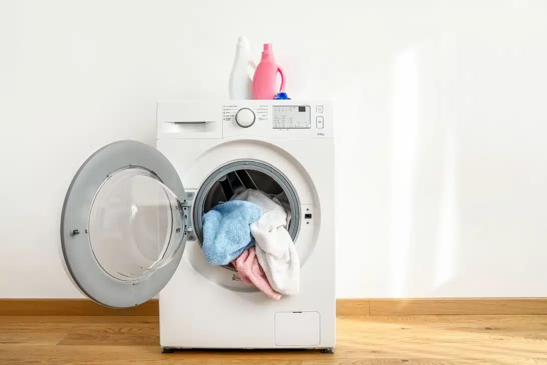 white open front loader washing machine with clean towels hanging out of it