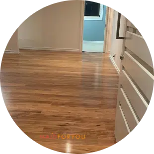A timber wood floor in a spacious, vacant living room, freshly cleaned.